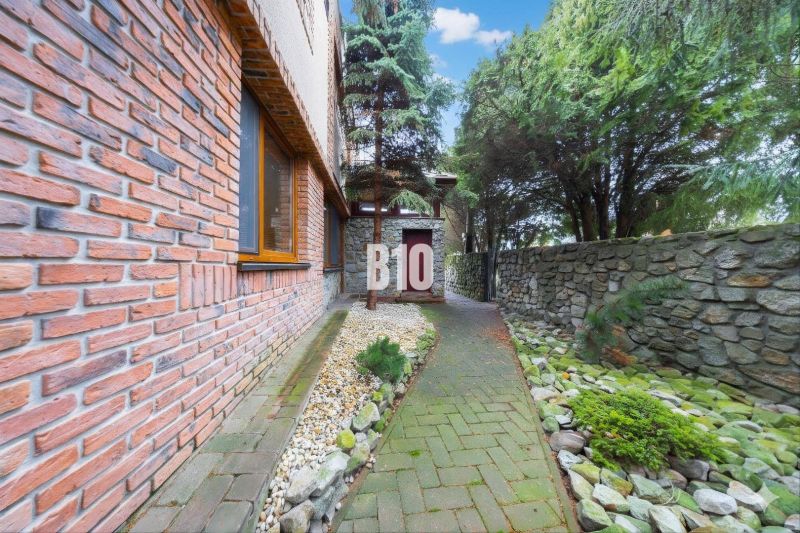 Ein Einfamilienhaus in Štvrtok na Ostrove mit Ziegelverkleidung und einem Steinweg im Garten.