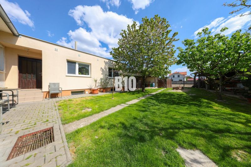 Exterieur eines Einfamilienhauses in Kalinkovo mit Rasen, Bäumen und Terrasse.