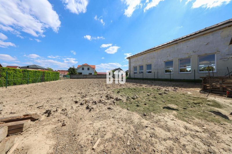 Grundstück mit Blick auf ein Einfamilienhaus in Kalinkovo, von Zäunen umgeben, blauer Himmel.