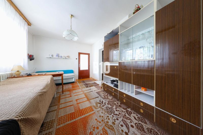 Innenraum eines Einfamilienhauses mit Sofa, Schrank und Esstisch, Teppich auf dem Boden.