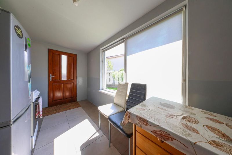Küche in einem Einfamilienhaus mit sonnigen Fenstern und einem Holztisch.