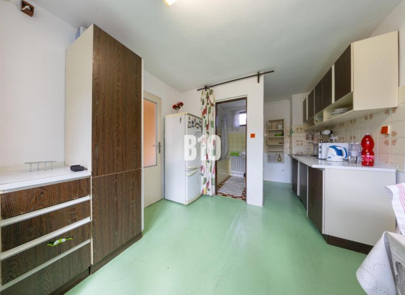 Küche in einem Einfamilienhaus mit grünem Boden und Holzdekor auf den Schränken.