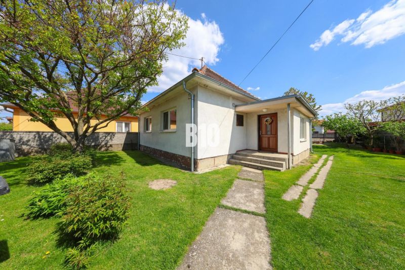 Ein Einfamilienhaus in Kalinkovo mit Vorgarten, Baum und Gehweg auf dem Rasen.