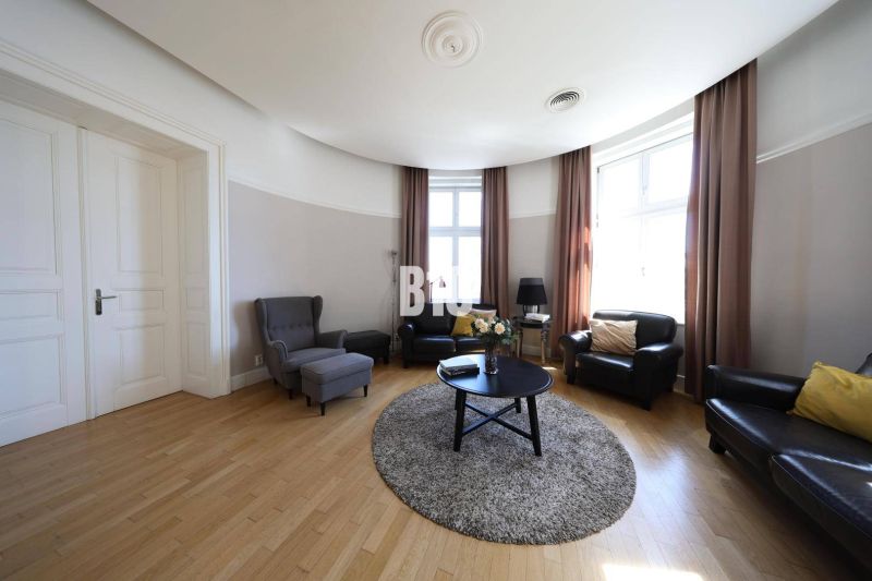 Wohnzimmer mit Holzboden, bequemen Sesseln und großem Fenster in einer 5-Zimmer-Wohnung.