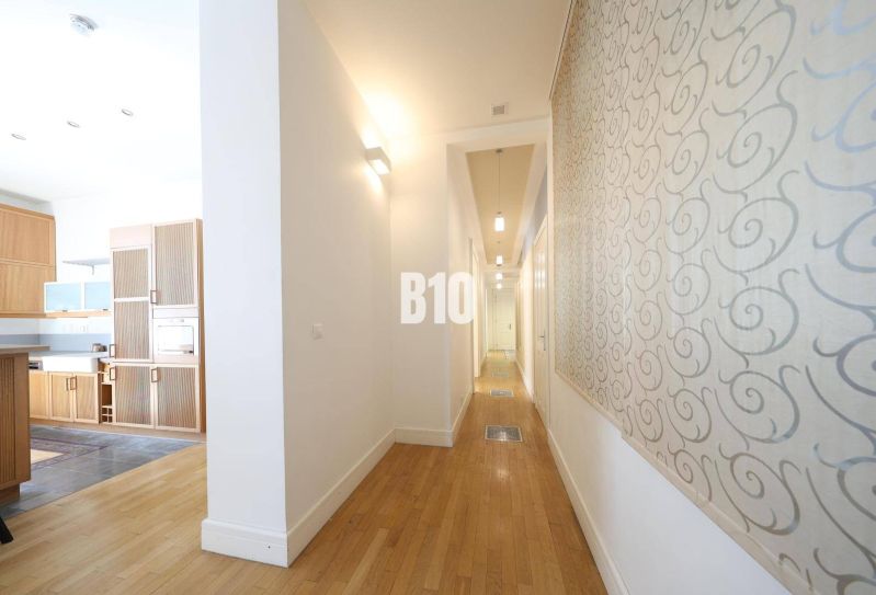 Der Flur in einer 5-Zimmer-Wohnung oder größer mit einem Boden in Holzoptik und einem Eingang zur Küche.