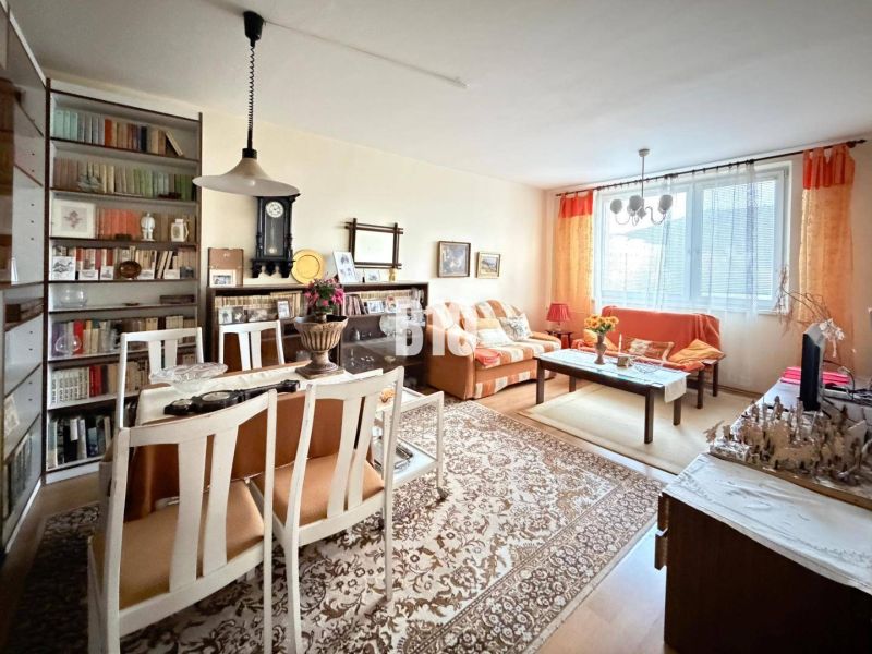 Wohnzimmer mit Esstisch und Regalen in einer 3-Zimmer-Wohnung mit Holzdekor-Boden.