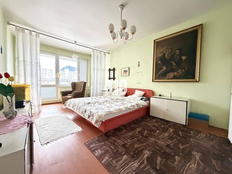 Ein Zimmer mit einem Doppelbett, einem Bild an der Wand und einem Boden mit Holzdekor.