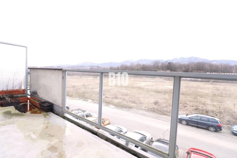 Blick auf die Umgebung von der Terrasse einer 2-Zimmer-Wohnung in Martin, Parkplatz und Feld am Horizont.