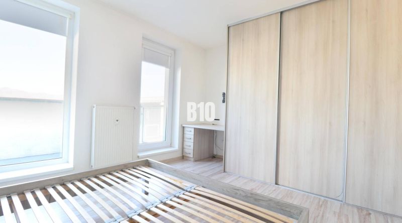 Schlafzimmer mit Holzboden in einer Zweizimmerwohnung, Kleiderschrank und Schreibtisch.