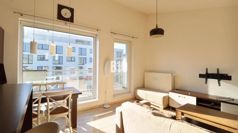 Wohnzimmer in einer 2-Zimmer-Wohnung mit hellen Möbeln und einem Boden in Holzoptik.