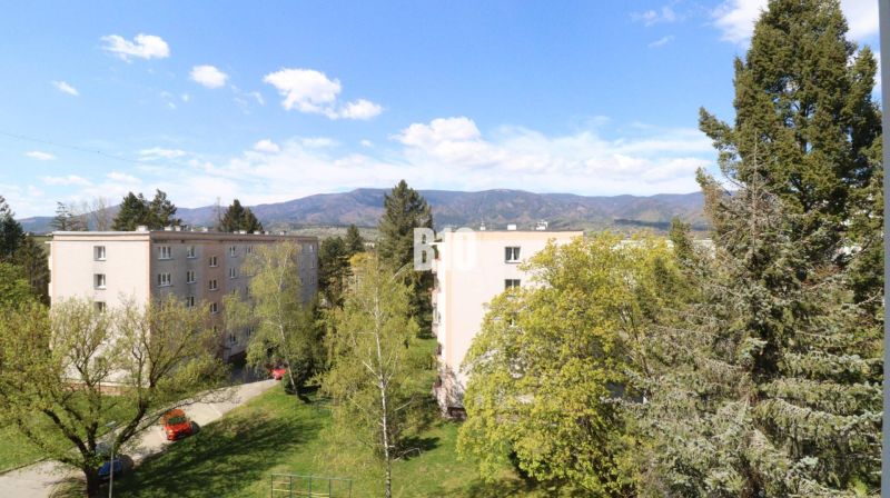 Blick auf Plattenbauten in Martin, umgeben von Grünflächen und Bergen im Hintergrund.