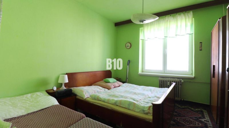 Grünes Schlafzimmer mit zwei Betten und Möbeln in einer 3-Zimmer-Wohnung.