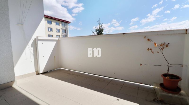 Balkon in einer 3-Zimmer-Wohnung. Pflanze im Blumentopf, Fliesen, teilweise Blick auf das Nachbargebäude.
