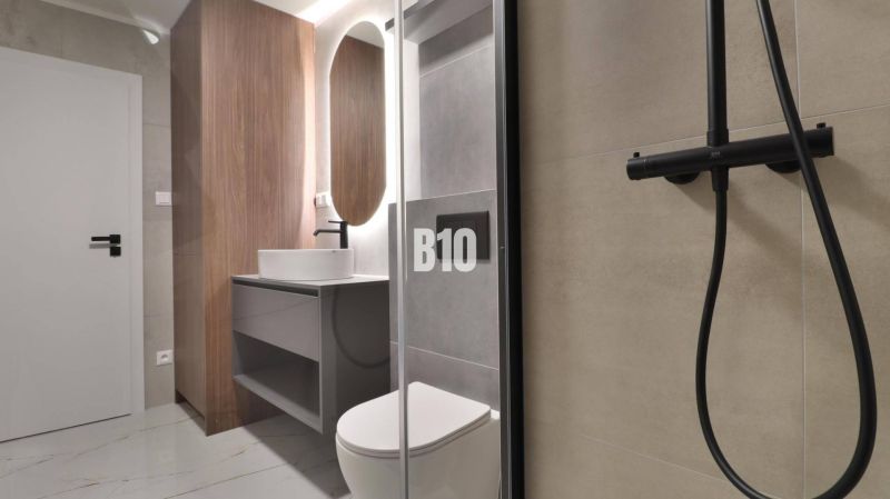 Badezimmer in einer 2-Zimmer-Wohnung mit Holzboden und Duschkabine.