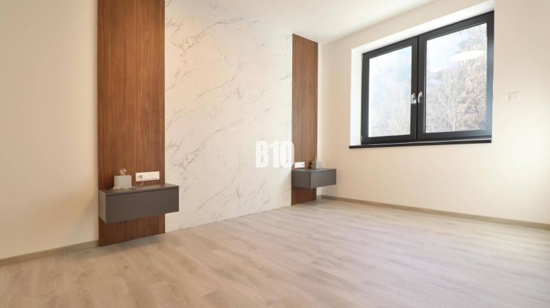 Dieses Zimmer in der 2-Zimmer-Wohnung hat einen Boden mit Holzdekor und eine Wand mit Marmoroptik.