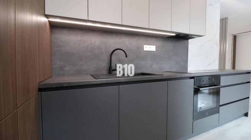 Küchenzeile in einer Zweizimmerwohnung mit schwarzem Spülbecken und eingebautem Ofen.