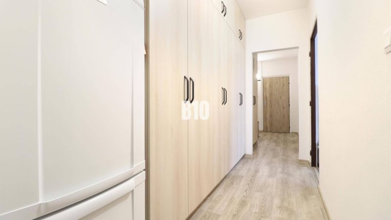 Der Flur in einer 3-Zimmer-Wohnung mit einem Boden in Holzoptik und hellen Schränken.