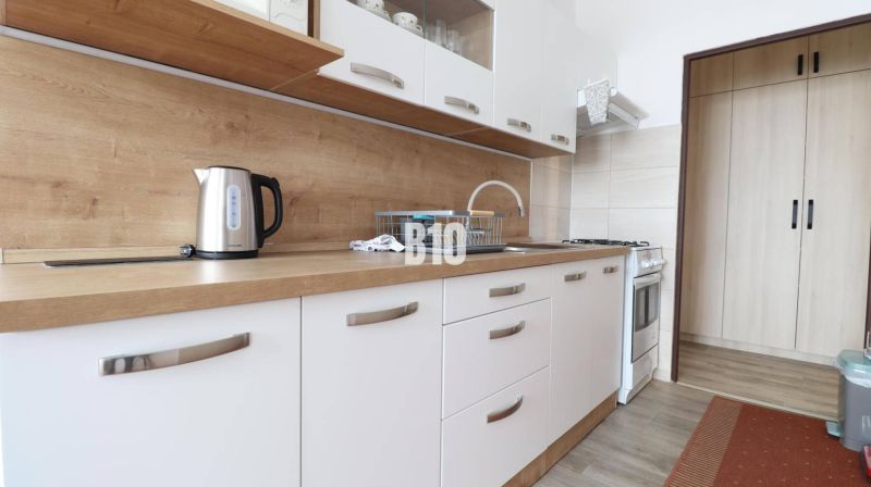 Helle Küche mit weißen Schränken und Arbeitsplatte mit Holzdekor in einer 3-Zimmer-Wohnung.