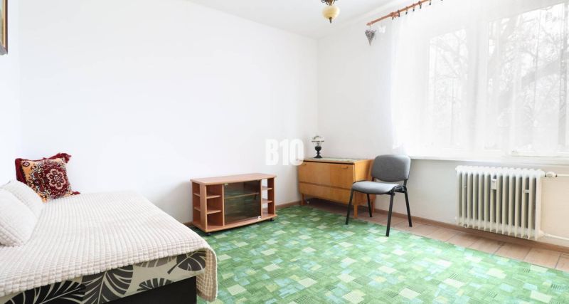 Innenraum einer 3-Zimmer-Wohnung mit Teppichboden, Sessel und Lampe am Fenster.