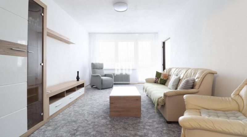 Wohnzimmer in einer 3-Zimmer-Wohnung mit einem bequemen Sofa und Ledersesseln.
