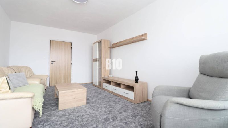 Wohnzimmer mit beigem Sofa, grauem Sessel und Möbeln mit Holzdekor in einer 3-Zimmer-Wohnung.