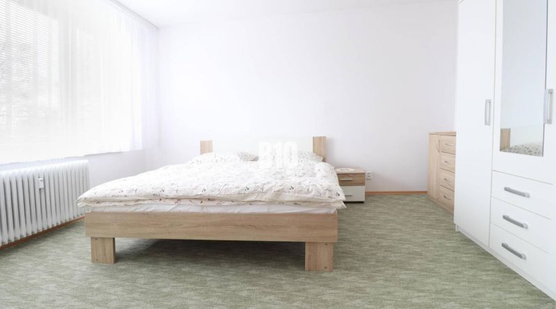 Schlafzimmer in einer 3-Zimmer-Wohnung mit Doppelbett, weißen Möbeln und Teppich.