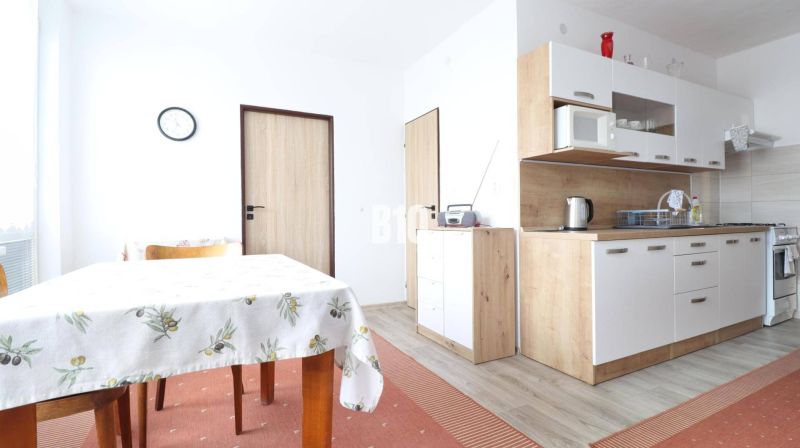 Die Küche in einer 3-Zimmer-Wohnung mit einem Boden in Holzoptik, einem Esstisch und Schränken.