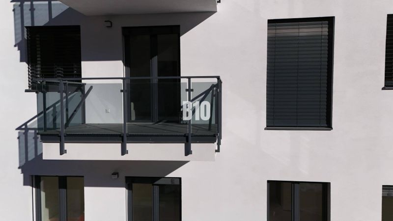 Balkon mit verglästem Geländer und Fensterläden an einem Gebäude einer Zweizimmerwohnung in Dolný Kubín.