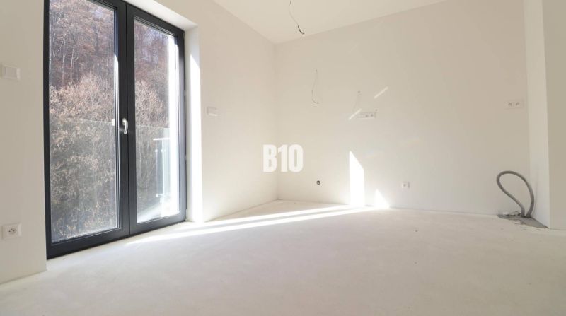 Ein leeres Zimmer in einer 3-Zimmer-Wohnung mit großen Fenstern und Blick auf die Natur.