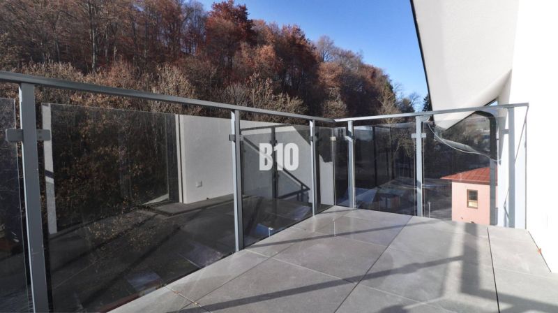 Balkon einer 2-Zimmer-Wohnung in Dolný Kubín mit Glasgeländer und von Bäumen umgeben.