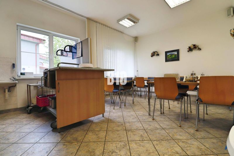Kantine in Produktionsräumen mit Holzstühlen und Waschbecken.