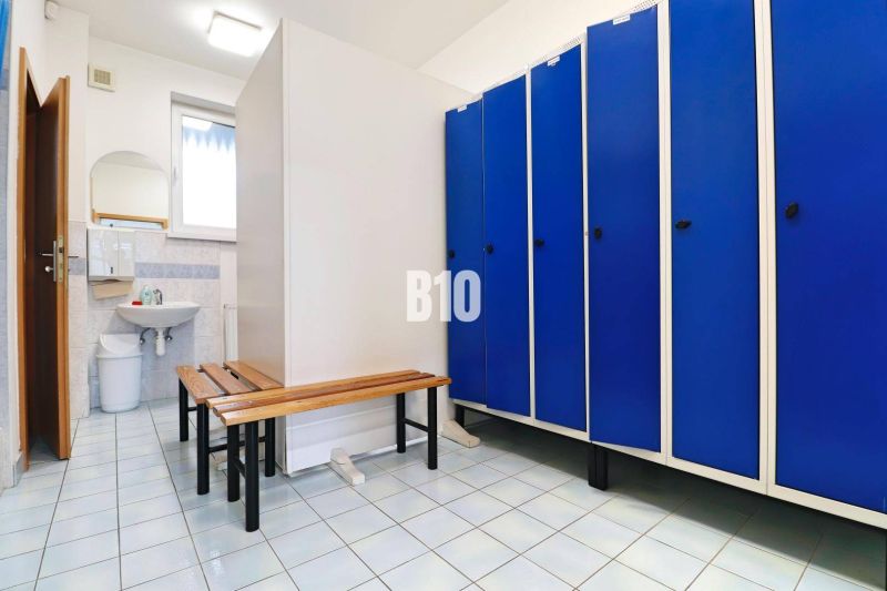 Umkleideraum in Produktionsräumen mit blauen Schränken und einem Spiegel über dem Waschbecken.