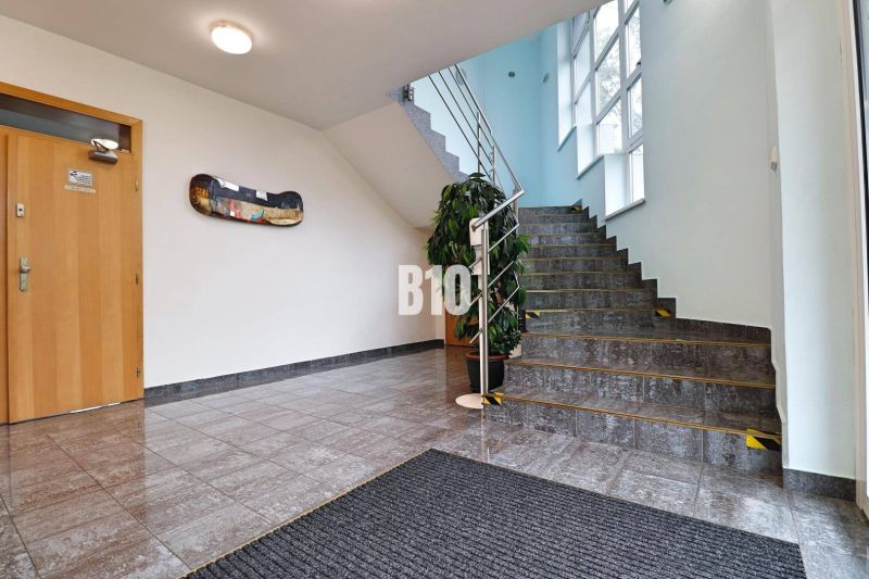 Innenraum eines Produktionsraums mit Treppe, Pflanze und Holztüren.