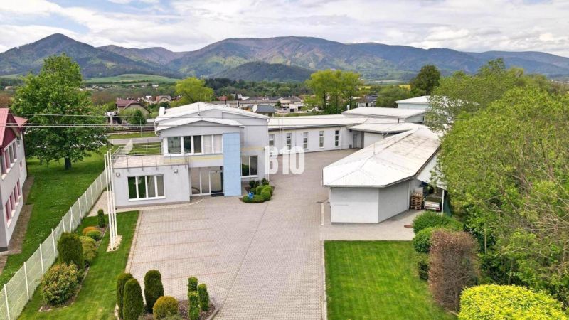 Produktionsräume in Košťany nad Turcom mit gepflegtem Garten und Bergkulisse.