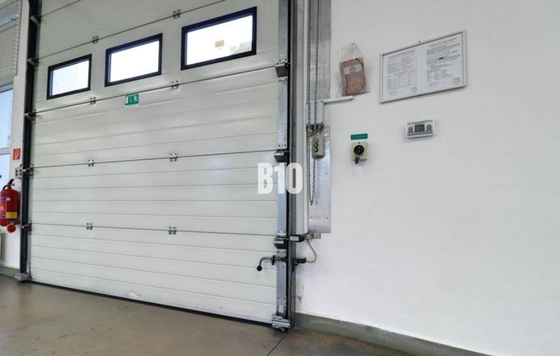 Industrielles Tor in Produktionsräumen mit Sicherheitsanweisungen an der Wand.