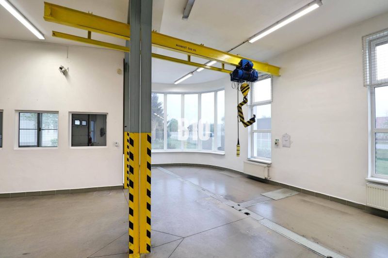 Ein Raum mit einem Kran in einer Produktionshalle mit Betonboden und großen Fenstern.