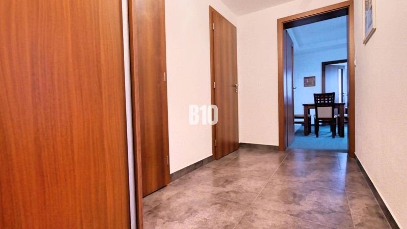Flur mit Fliesen und Türen, die in ein Zimmer in einer 3-Zimmer-Wohnung führen.