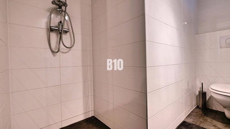 Badezimmer in einer 3-Zimmer-Wohnung mit weißen Fliesen, Dusche und Toilette.