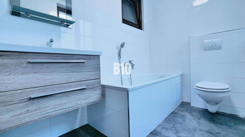 Badezimmer in einer 3-Zimmer-Wohnung mit Badewanne, Waschbecken, WC und einem Boden in Holzoptik.