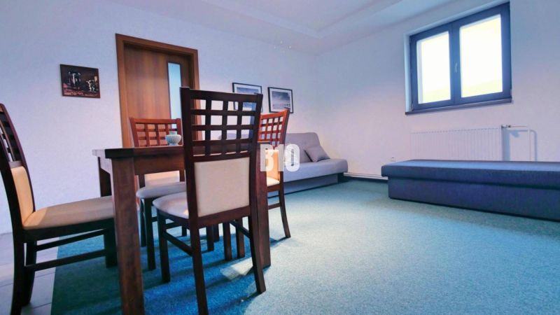 Esszimmer in einer 3-Zimmer-Wohnung mit Holzmöbeln und blauem Bodenbelag.