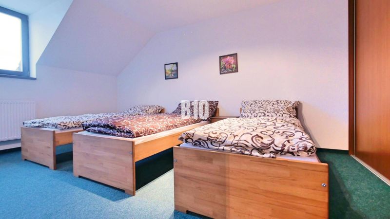 Schlafzimmer mit drei Betten in einer 3-Zimmer-Wohnung. Holzdekorationen, grüner Teppich.