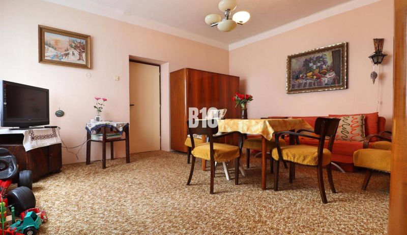 Wohnzimmer in einem Einfamilienhaus, Teppiche, Möbel aus dunklem Holz, Bilder an den Wänden.