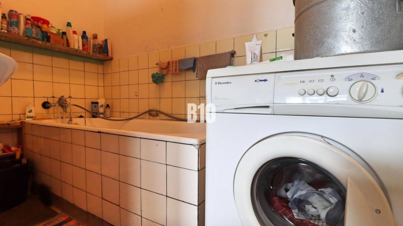 Badezimmer in einem Einfamilienhaus mit Badewanne, Waschmaschine und Reinigungsmitteln auf dem Regal.