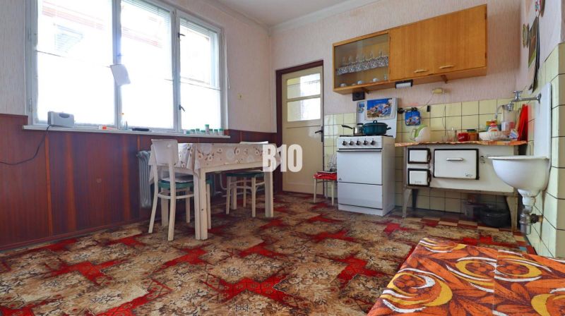 Eine Küche in einem Einfamilienhaus mit Retro-Möbeln, Kacheln und einem auffälligen Teppich.