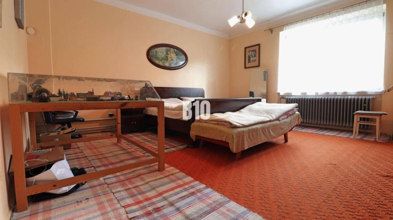 Ein Zimmer in einem Einfamilienhaus mit einem Bett, einem Tisch, einer Modelleisenbahn und Teppichen.
