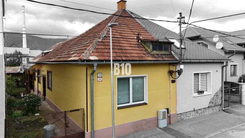 Ein Einfamilienhaus in Martin mit gelber Fassade und schrägem Dach, neben dem Zugangsweg.