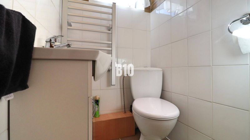 Badezimmer in einem Einfamilienhaus mit weißen Fliesen, Waschbecken und WC.