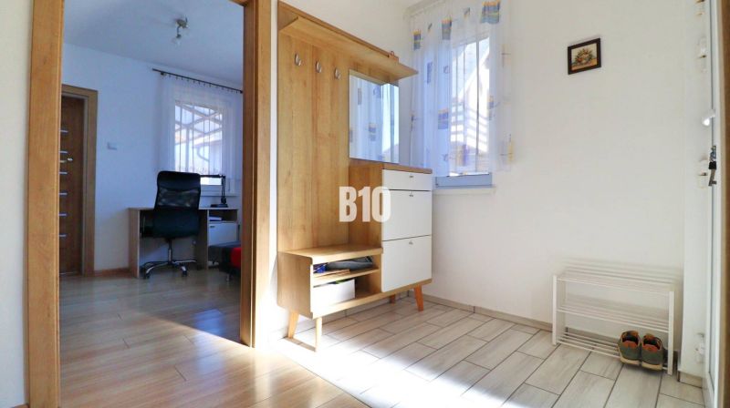 Eingangsbereich in einem Einfamilienhaus mit Holzelementen und Blick auf das Arbeitszimmer.