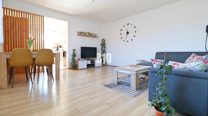 Wohnzimmer in einem Einfamilienhaus mit Holzboden, Esstisch und Sofa.
