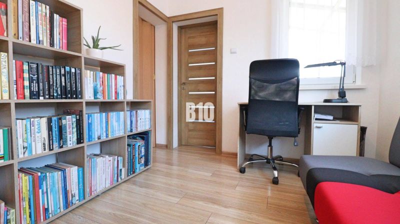 Bibliothek, Schreibtisch und Sessel in einem Einfamilienhaus mit Holzboden.